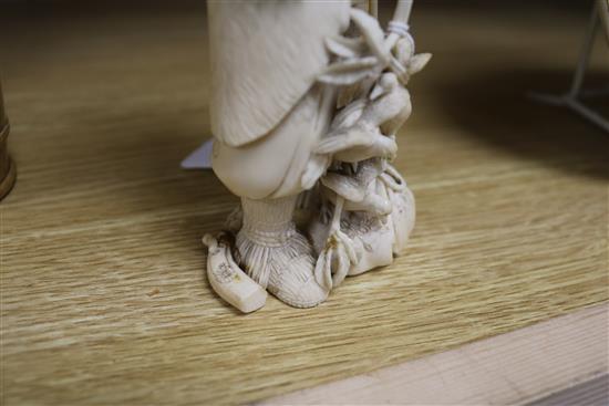 A Japanese carved ivory okimono of a huntsman, Meiji period, holding a hawk and a brace of birds